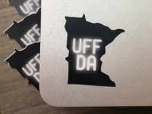 Load image into Gallery viewer, mage: Black die-cut sticker in the shape of the U.S. state of Minnesota. The word “UFFDA” is in the center of the sticker in glowing, white lettering
